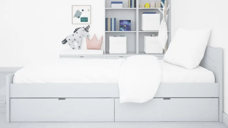 A white bed featuring a white headboard and integrated drawers, creating a clean and minimalist bedroom aesthetic.
